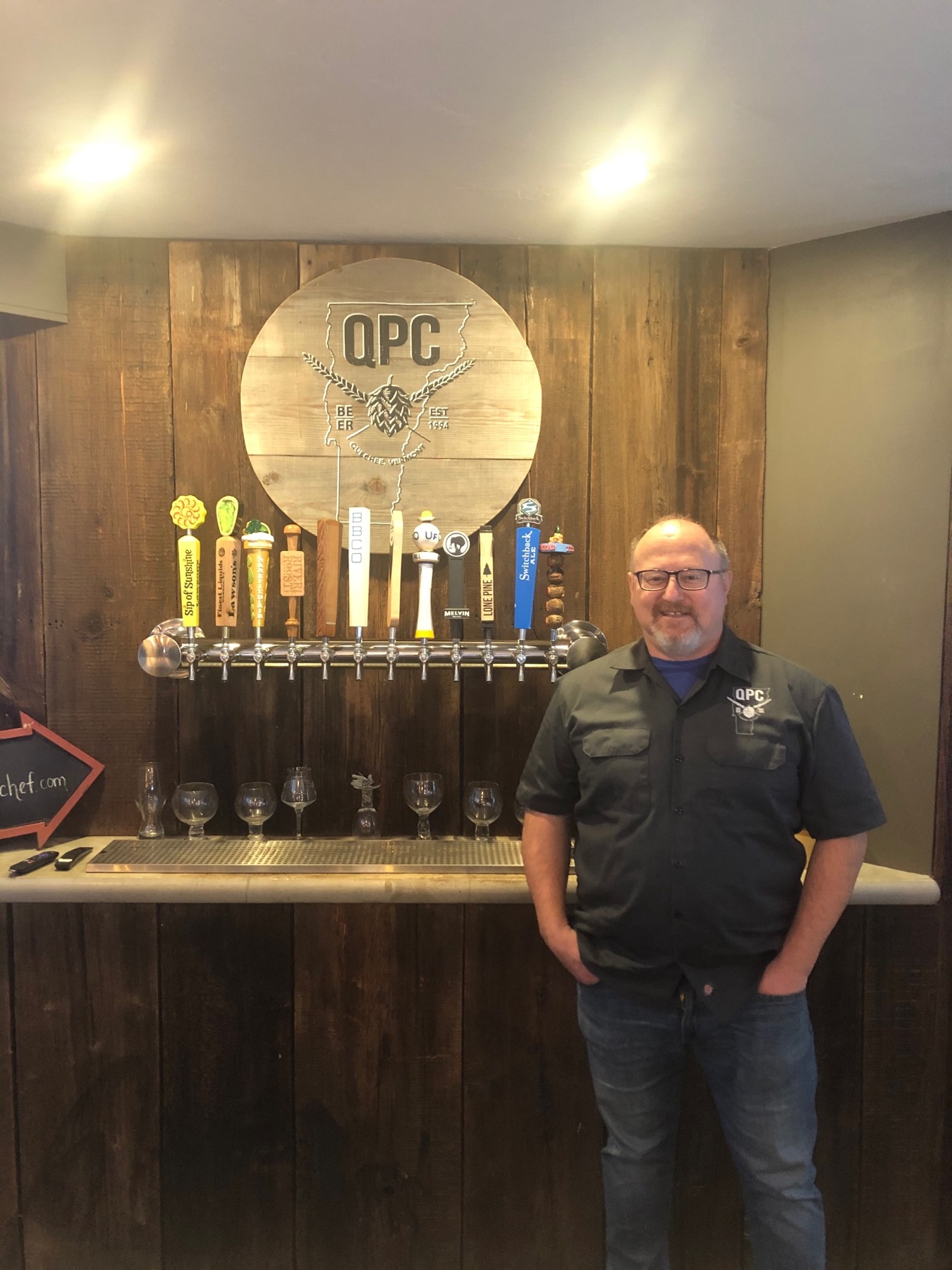 Owner Nick Tsouknakis stands in front of the taps at Quechee Pizza Chef.